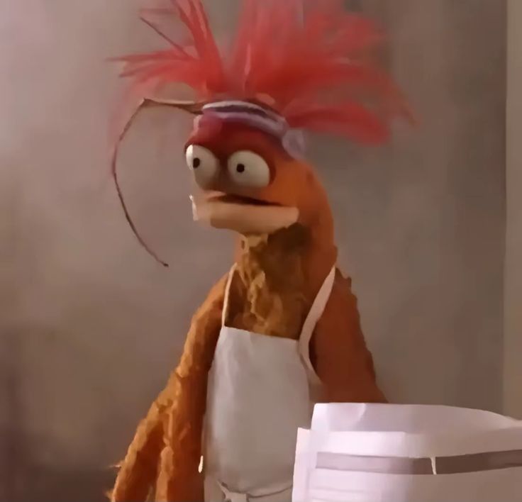 Image of Pepe the King Prawn, a puppet with crazy orange hair, an apron, and horrified eyes looking off to the side.