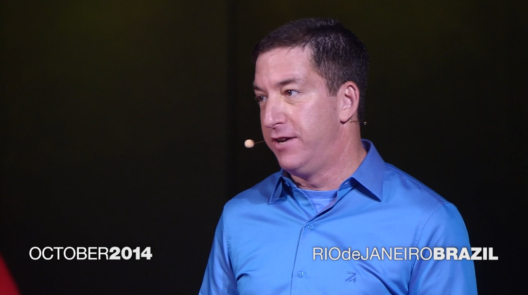 Glenn Greenwald, a white man with short, dark hair and a blue shirt gives a TedTalk. The date says October 2014 in one corner, and the other corner says the location – Rio de Janeiro, Brazil.